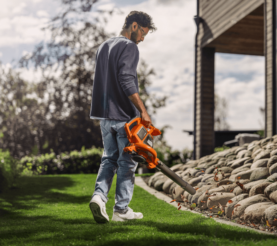 Man blowing leaves in the backyard